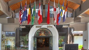 A hotel entrance with multiple national flags, a reception desk, and a bellhop cart. - The Lodge at Vail, a RockResort by Vail Resorts (Vail)