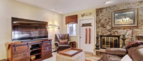 A living room with a flat-screen TV, leather sofa, and a stone wall.
