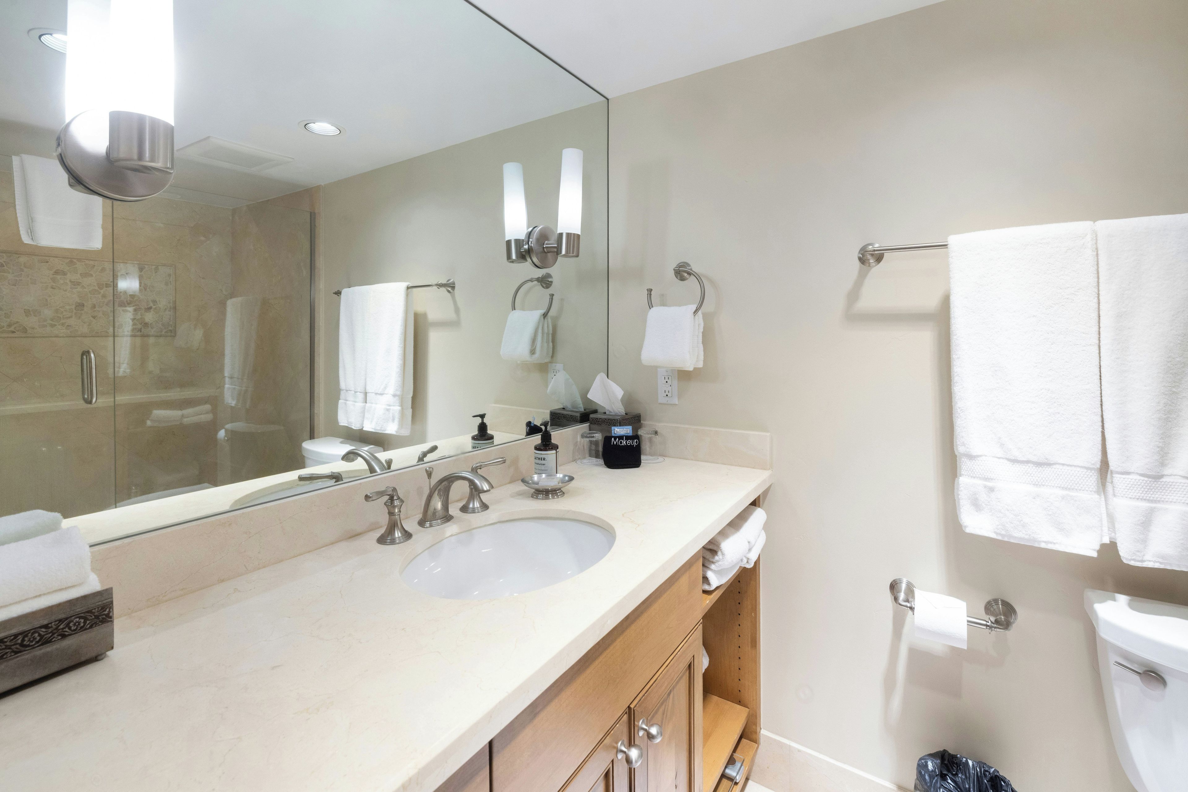 A modern bathroom with a large mirror, a double sink, and a toilet.