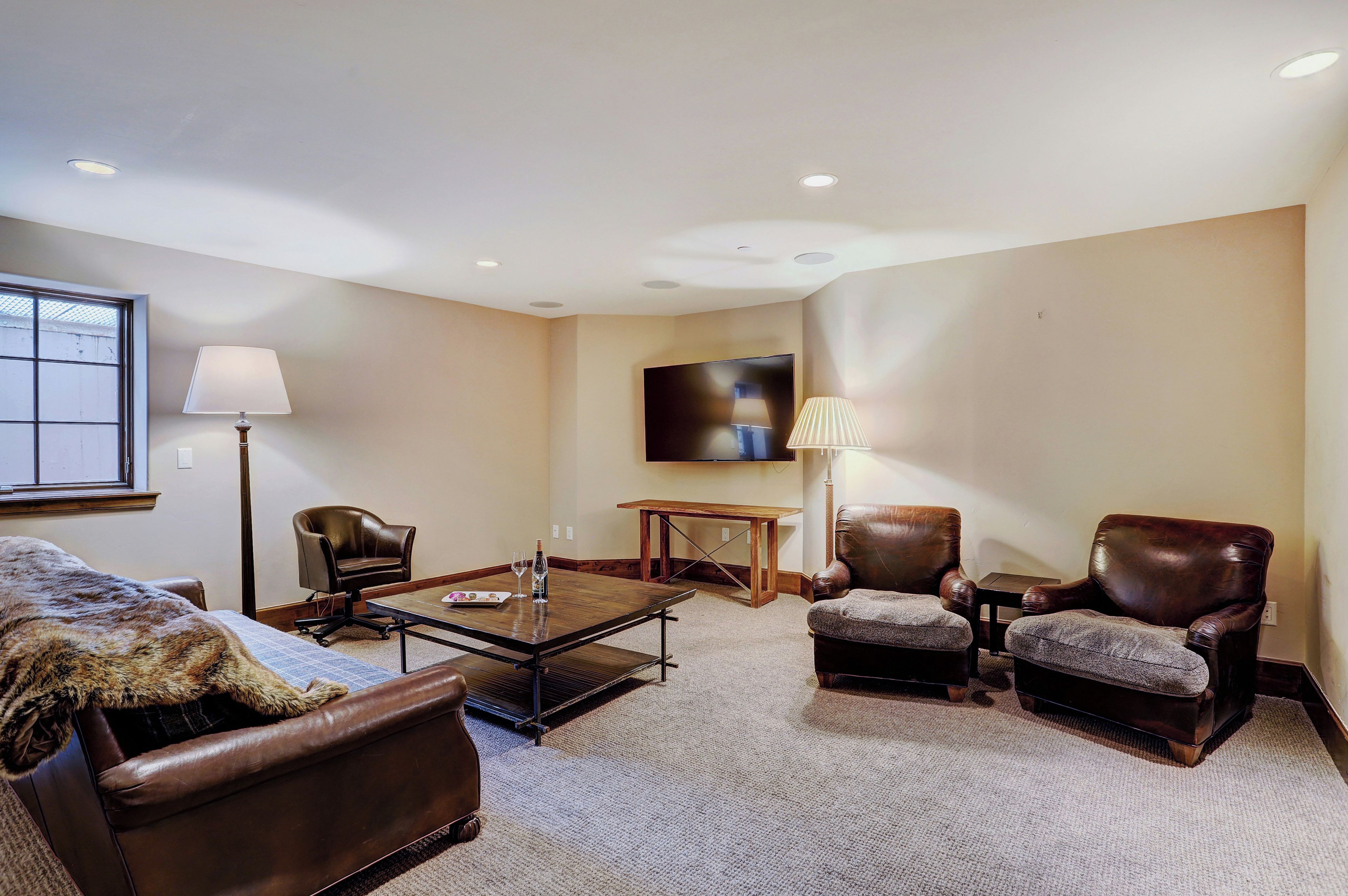 A living room with a sofa, armchairs, a coffee table, a TV, and a lamp.