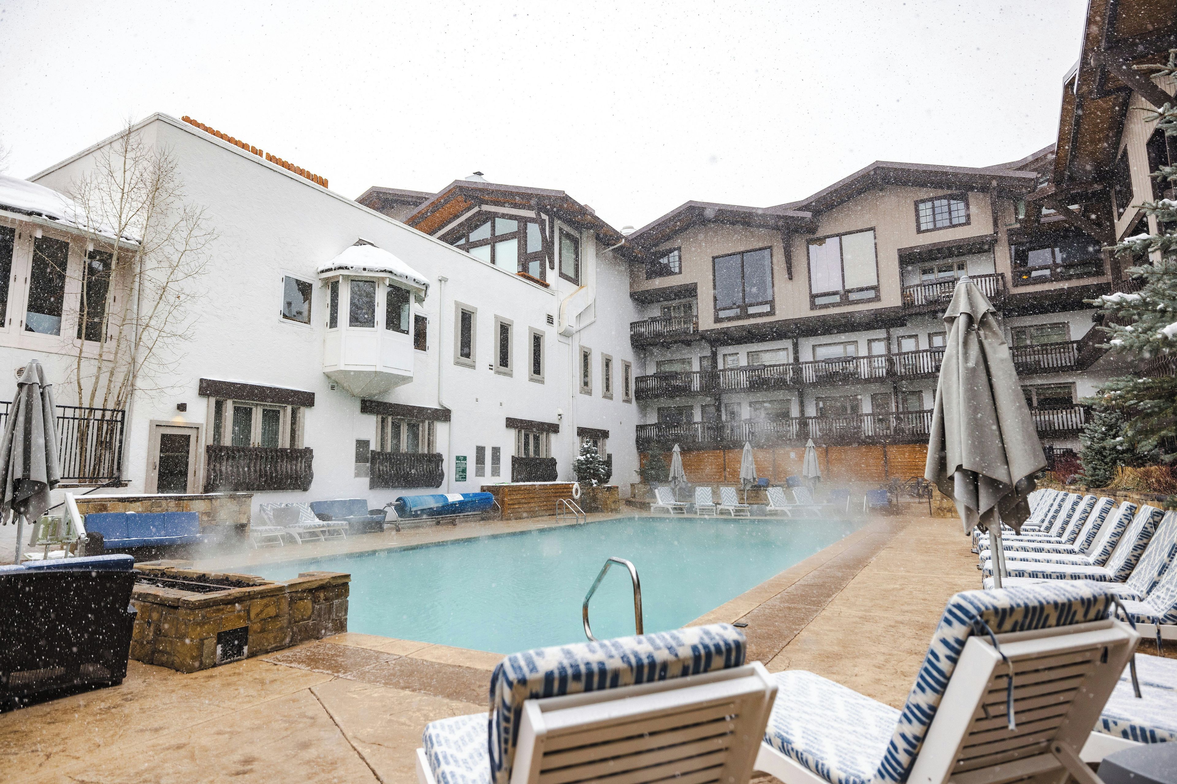 A pool area with lounge chairs and a hot tub, surrounded by buildings with balconies.