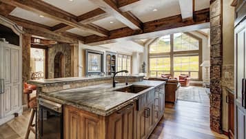 A spacious kitchen with a large island, wooden beams, and a stone accent wall.