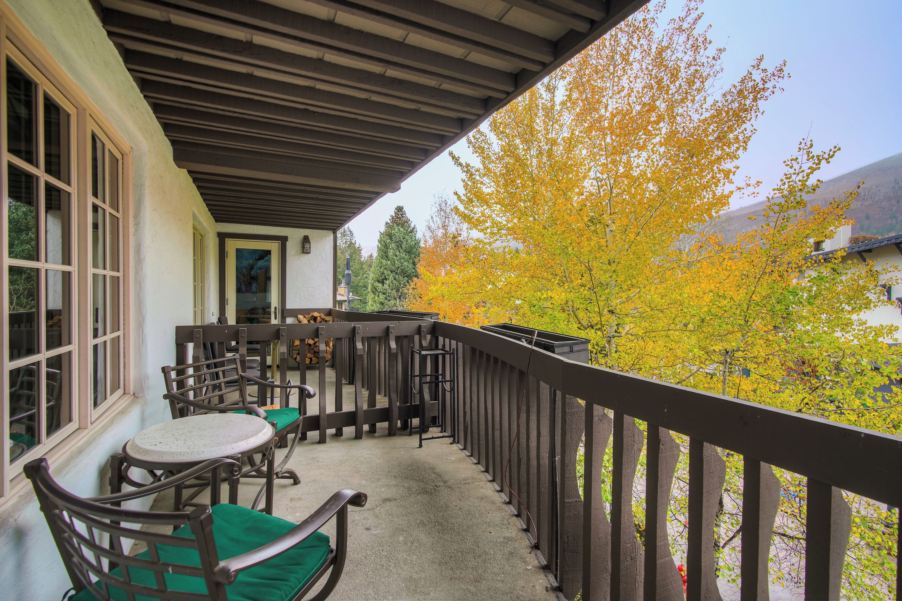 A covered outdoor area with a wooden deck, chairs, and a table.
