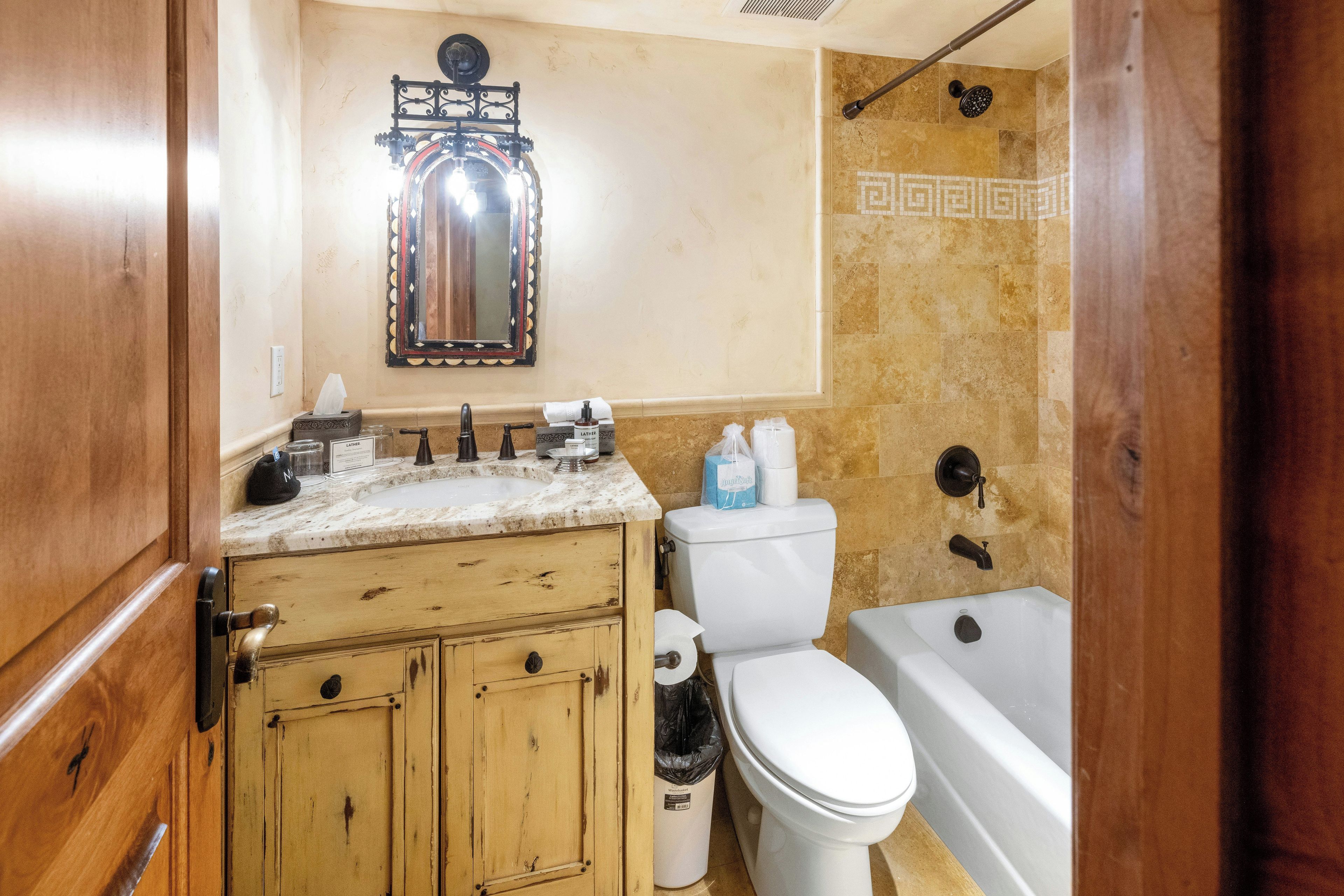 A bathroom with a wooden vanity, a mirror, a toilet, and a bathtub.