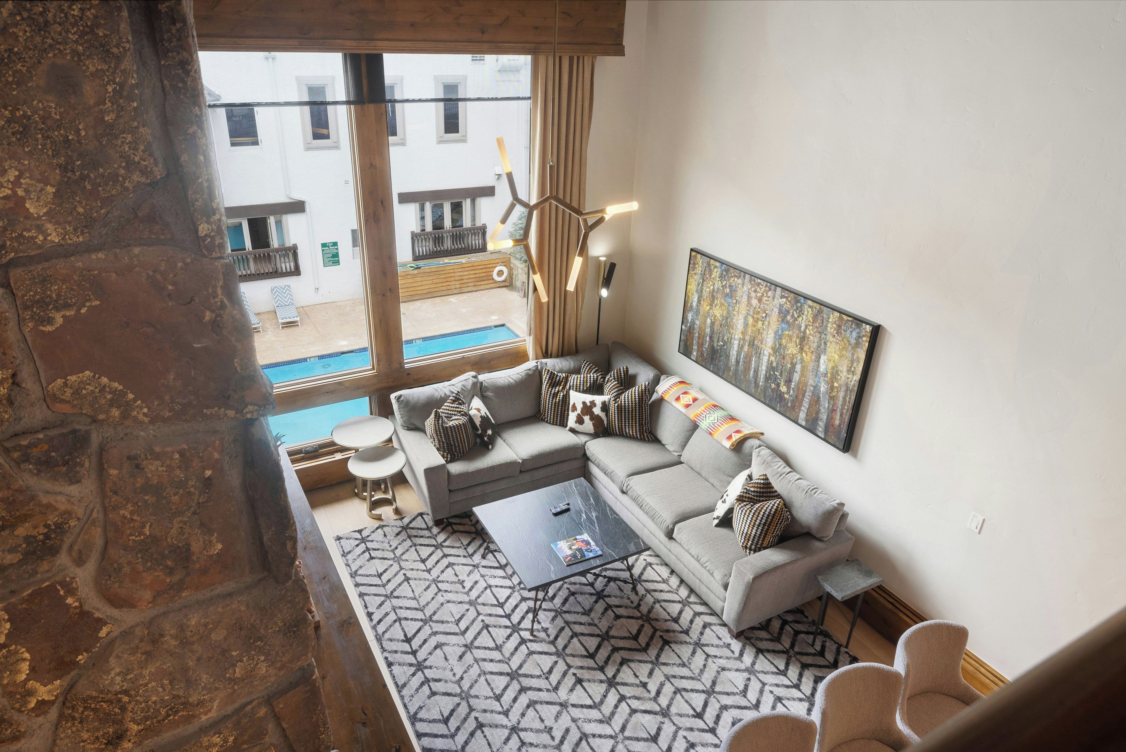 A modern living room with a sectional sofa, a coffee table, and a view of a pool outside.