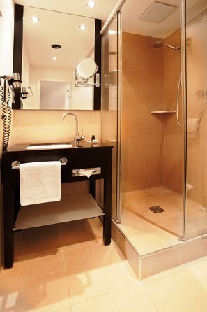 Ein modernes Badezimmer mit einer Duschkabine, einem Waschtisch mit Spiegel und einem Handtuch am Waschbecken.