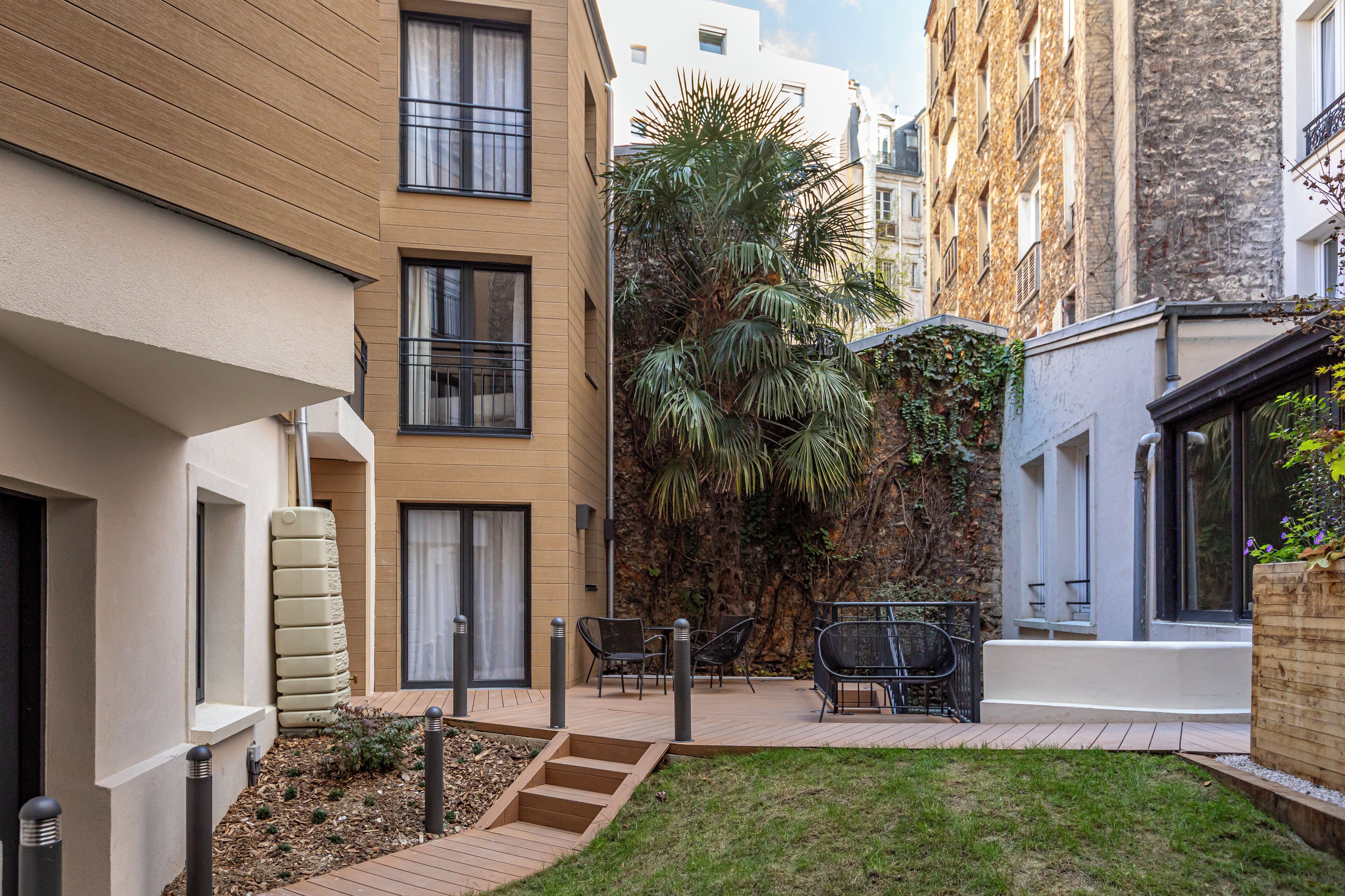 A courtyard with a small lawn, outdoor seating, and a palm tree.