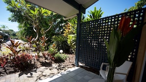 A patio area with a tiled floor, a white table, a chair, and a potted plant.