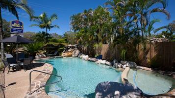 A pool area with lounge chairs, a sign for Best Western, and palm trees.
