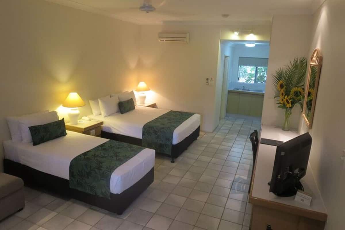 A hotel room with two beds, a desk, a chair, a TV, and a bathroom visible through an open door.