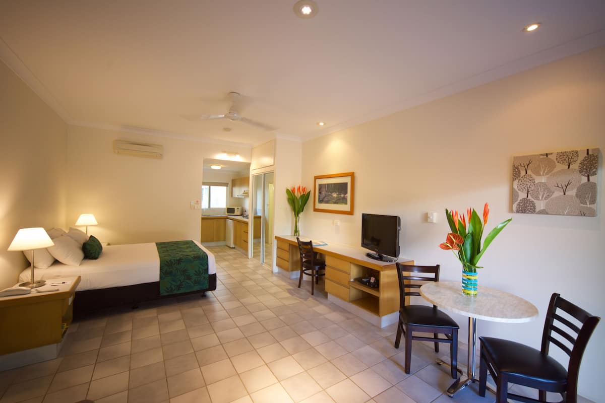 A hotel room with a bed, desk, TV, and seating area.