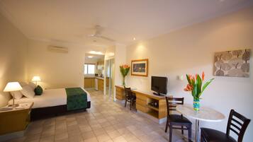 A hotel room with a bed, desk, TV, and seating area.