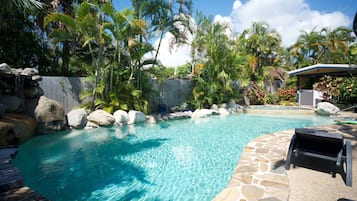 Una piscina al aire libre, sombrillas, sillones reclinables de piscina