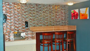 A kitchen with a tiled backsplash, a sink, and wooden bar stools. - Stay Express Inn Dallas - Fair Park / Downtown (Dallas)