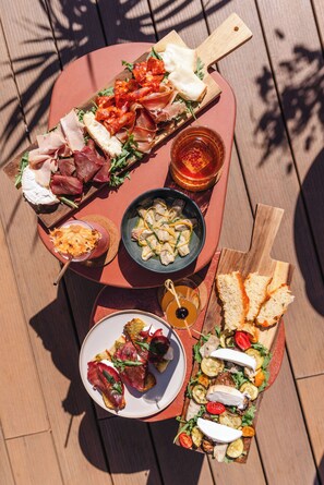 A wooden table with various food items including meats, cheeses, and vegetables, arranged on a wooden board. - Pley Hotel (Paris)
