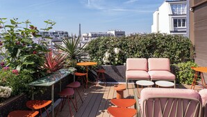 A rooftop terrace with seating, plants, and a view of the Eiffel Tower. - Pley Hotel (Paris)