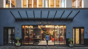 L'ingresso dell'hotel Pley, dal design moderno, con vetrate e un'area salotto interna ben visibile.