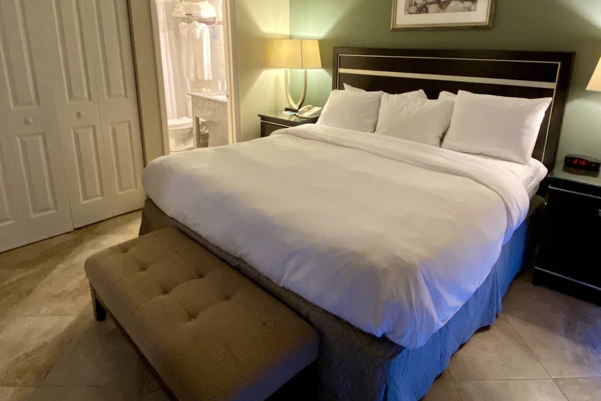 A neatly made bed with a matching bench, a bedside table with a lamp, and a framed picture on the wall.