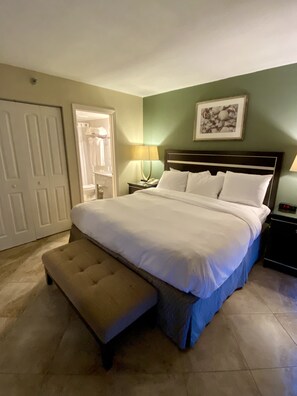 A neatly made bed with a matching bench, a bedside table with a lamp, and a framed picture on the wall.