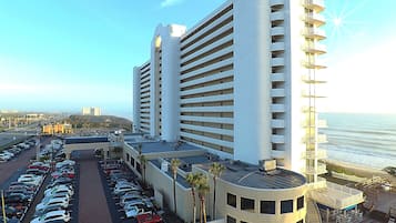 A high-rise hotel with a rooftop deck overlooking the ocean.