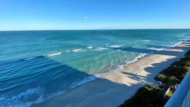 Una playa con agua azul cristalina y una orilla arenosa.