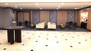 Un hall con una mesa redonda, dos sofás, un jarrón decorativo y una pared con diseño.