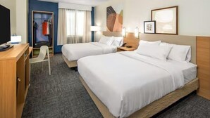 Une chambre d’hôtel avec deux lits, un bureau, une chaise et une armoire.