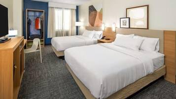 A hotel room with two beds, a desk, a chair, and a wardrobe.