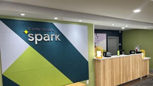 A reception desk with a 'spark' sign, a wooden bench, and a green wall.