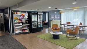 Un espace de détente moderne, doté de sièges confortables, d’un réfrigérateur rempli de collations et offrant une vue sur l’extérieur.