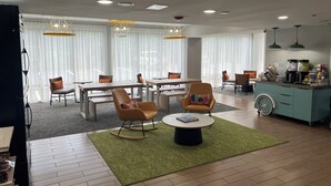 A modern hotel room with a dining area, a coffee station, and a seating area with a coffee table.