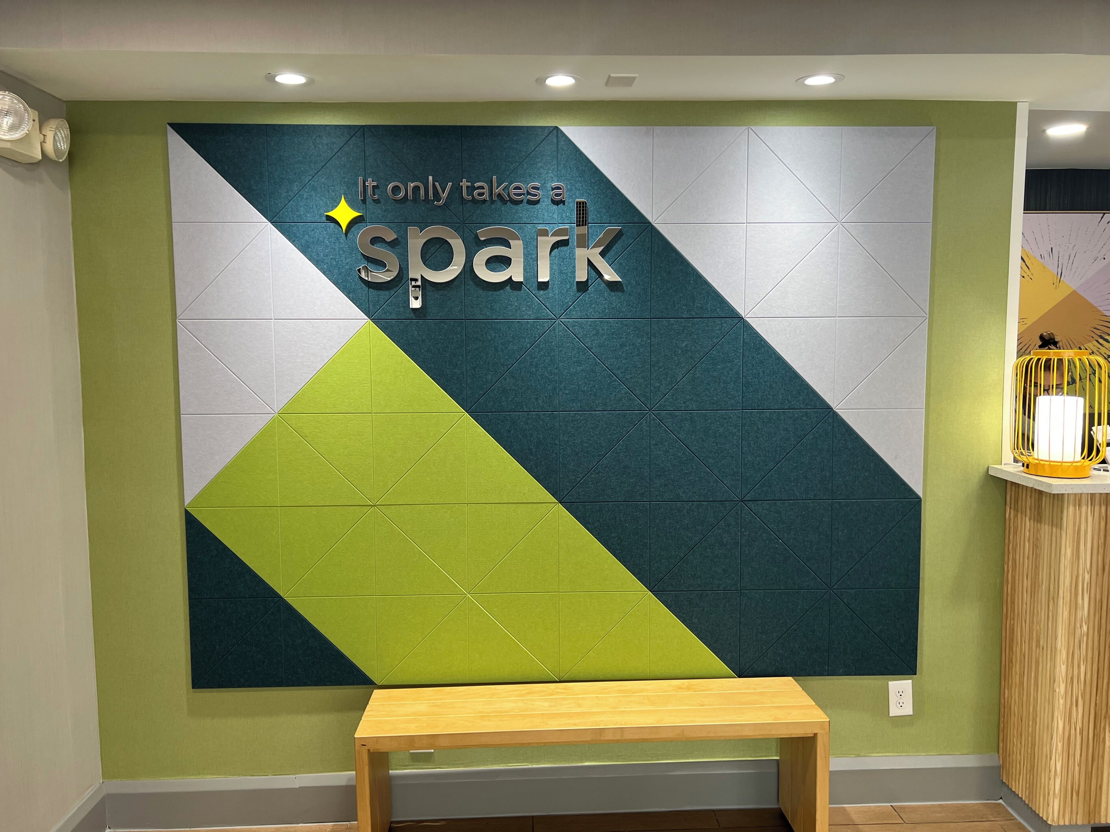 En væg med et geometrisk mønster og teksten 'It only takes a spark'.