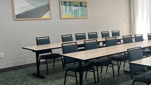 A conference room with a long table and chairs, ceiling lights, and two abstract paintings on the wall.