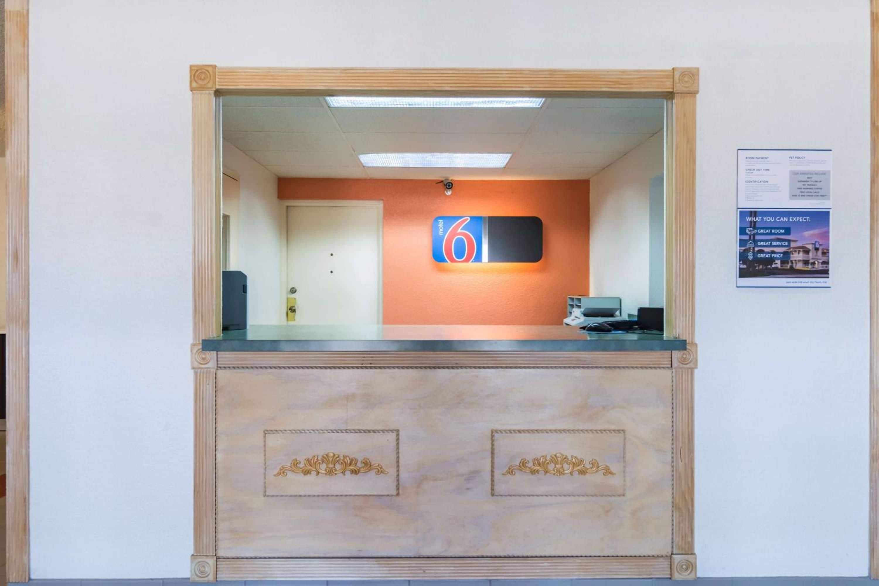 A reception desk with a sign indicating room number 6, a door, and a notice board with information.