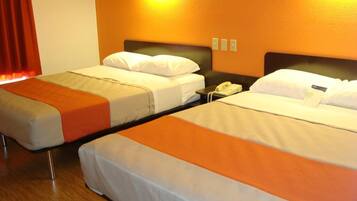 Two single beds with white bedding and orange accents, a bedside phone, and a wall-mounted light fixture.