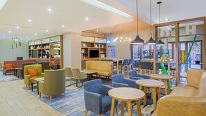 Un espace de détente moderne, doté de sièges, de tables et d’une bibliothèque.