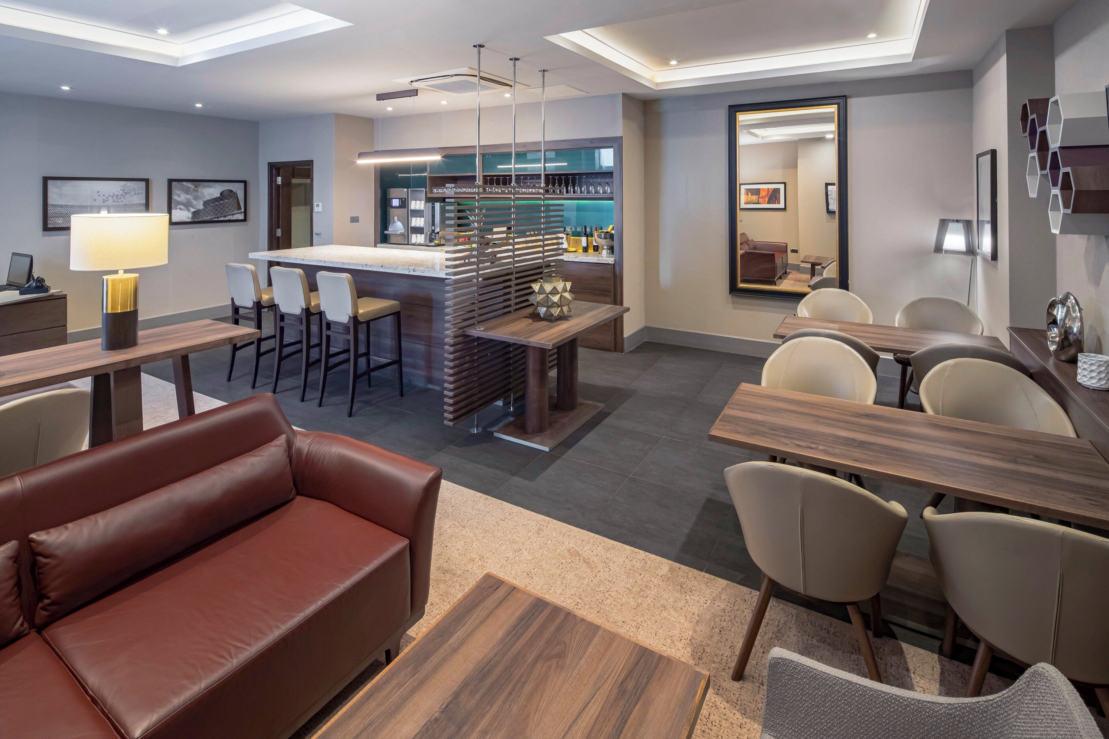 Un moderno vestíbulo de hotel con zona de bar, asientos y una kitchenette.