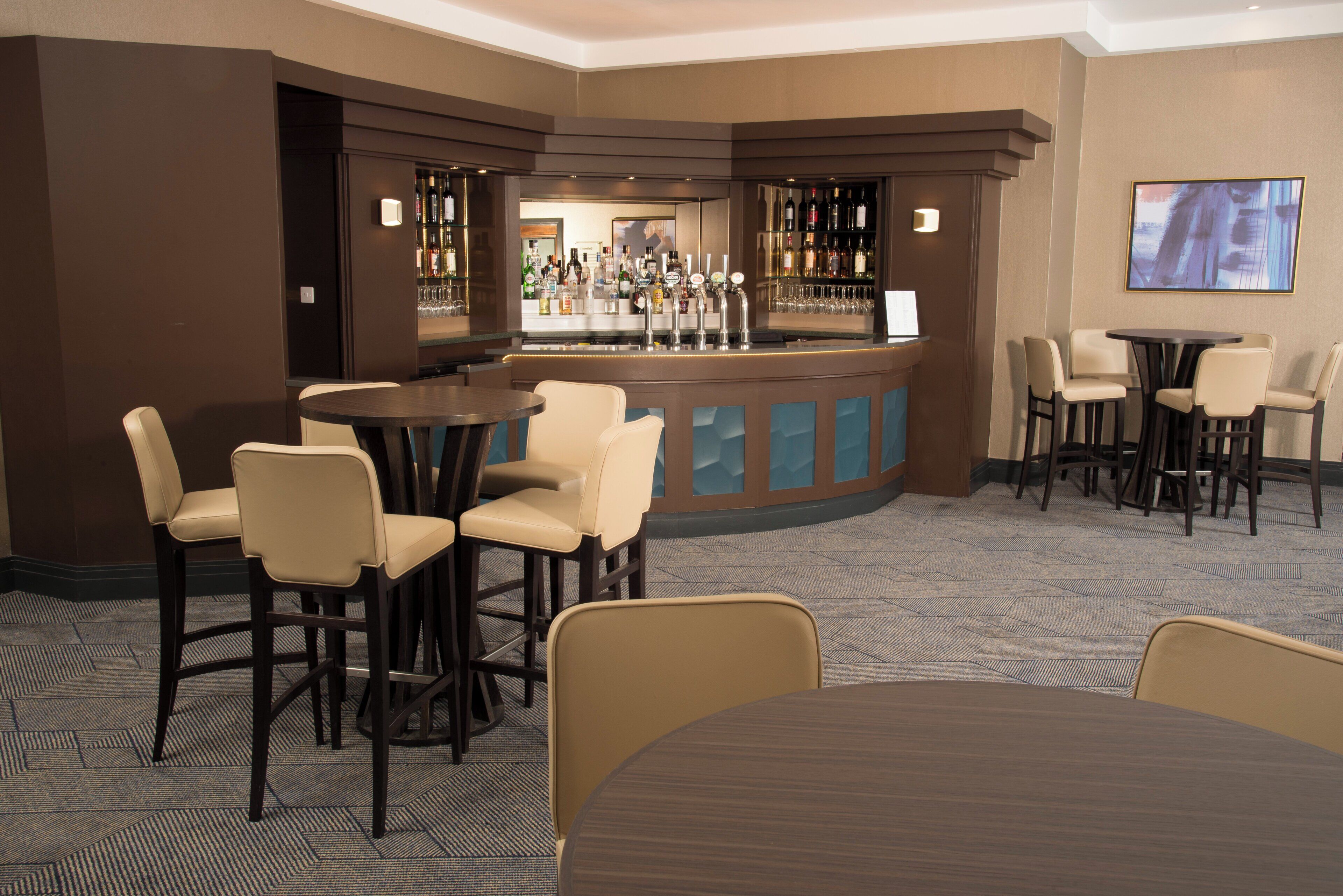 A bar area with multiple seating options, including bar stools and chairs, and a counter with a variety of bottles.