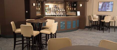 A bar area with multiple seating options, including bar stools and chairs, and a counter with a variety of bottles.