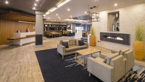 Un hall d’hôtel moderne comprenant un comptoir d’accueil, un espace salon et une cheminée.