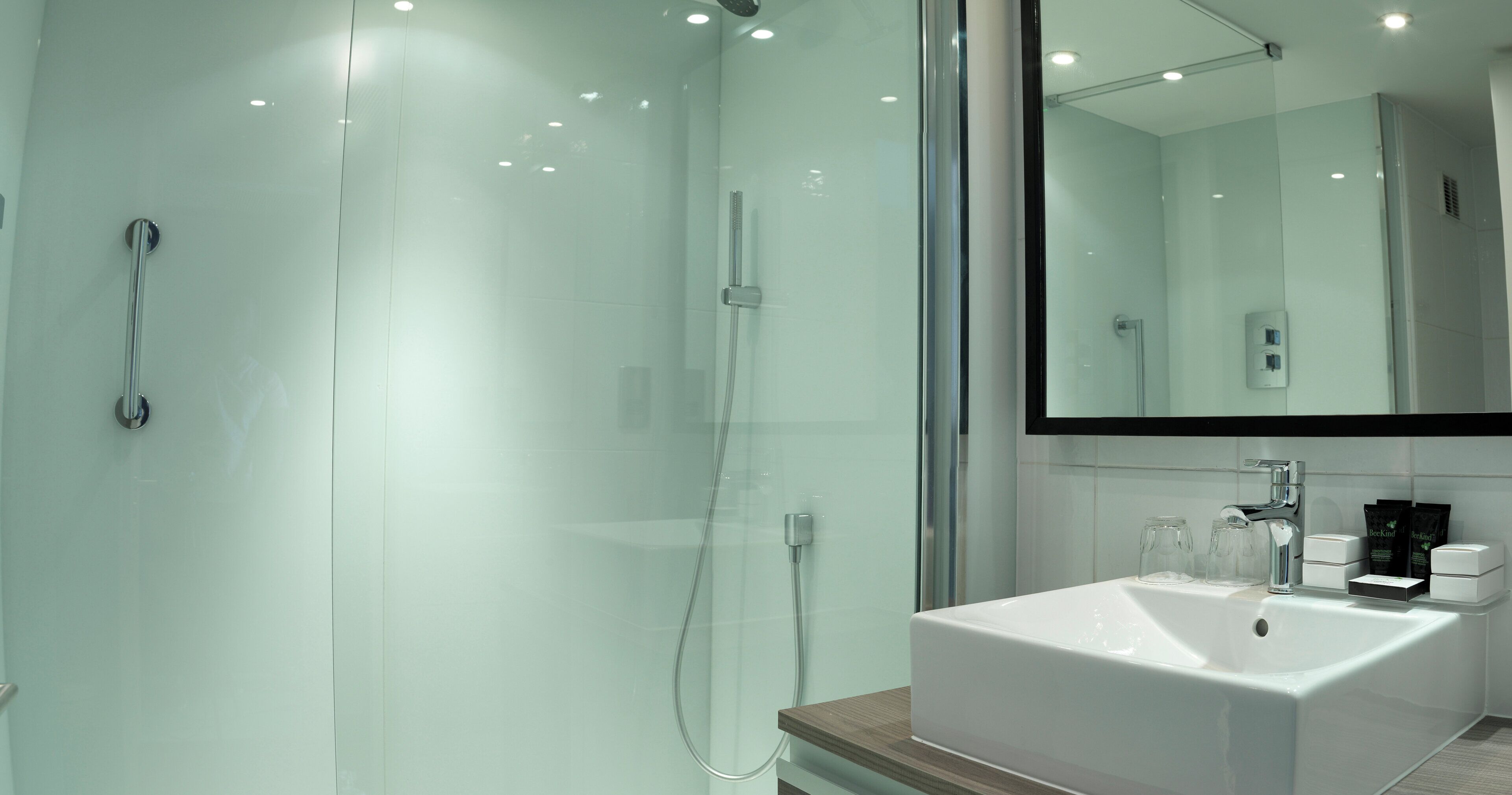 A modern bathroom with a glass-enclosed shower, a white sink, and a mirror above the sink.
