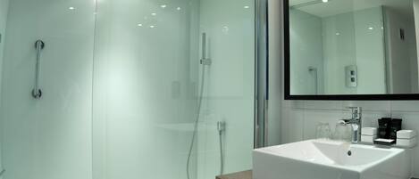 A modern bathroom with a glass-enclosed shower, a white sink, and a mirror above the sink.