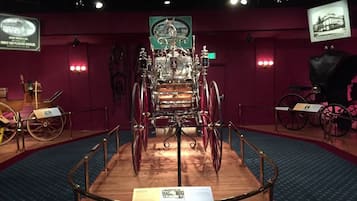 A museum exhibit with a central display of a large, ornate vehicle surrounded by smaller exhibits and informational plaques.