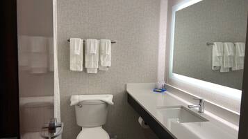 A bathroom with a toilet, a sink, a mirror, and towels hanging on a rack.