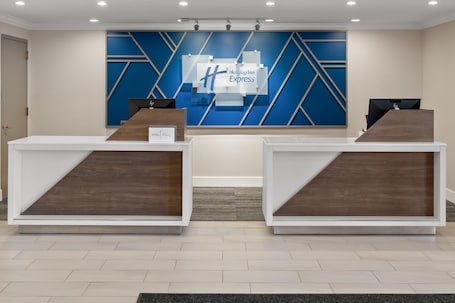 A reception desk with a blue geometric wall design and a Holiday Inn Express logo.