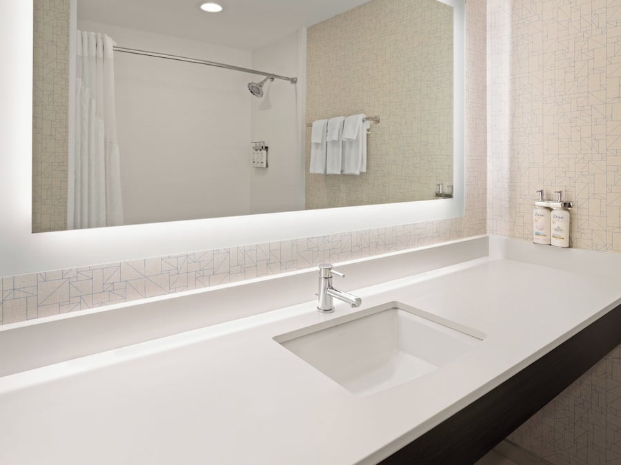 Un baño moderno con un espejo grande, un lavabo blanco y una zona de ducha.