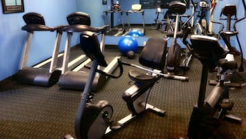 Une salle de sport équipée de divers appareils d’exercice, notamment des tapis de course, des vélos d’appartement et des poids libres.
