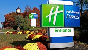 A Holiday Inn Express entrance sign with a clock and a flower bed. - Holiday Inn Express Stony Brook by IHG (Centereach)