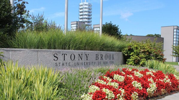 A sign for Stony Brook State University of New York surrounded by greenery and flowers. - Holiday Inn Express Stony Brook by IHG (Centereach)