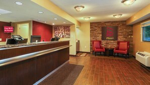 A hotel reception area with a reception desk, a 'Free Wi-Fi All Rooms' sign, a 'Red Roof Plus+' sign, and two red chairs. - Red Roof Inn PLUS+ Washington DC - Oxon Hill (Oxon Hill)
